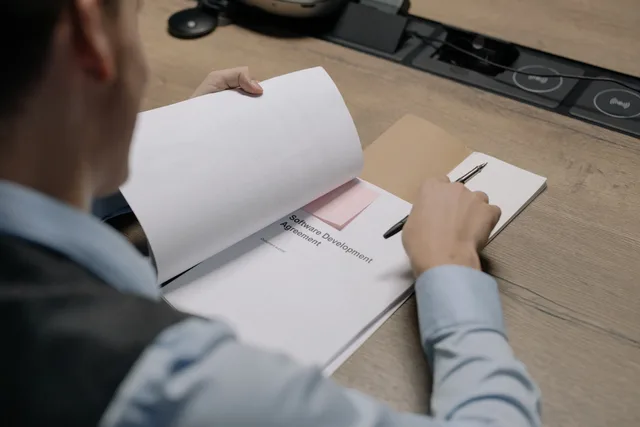 Business professional at the desk examining a software development agreement document. Due diligence on a payroll vendor, from entity identity to a clean exit